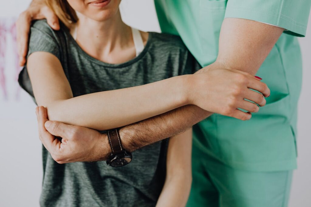 Kinésithérapeute aidant une femme à mobiliser son épaule avec une prothèse. 